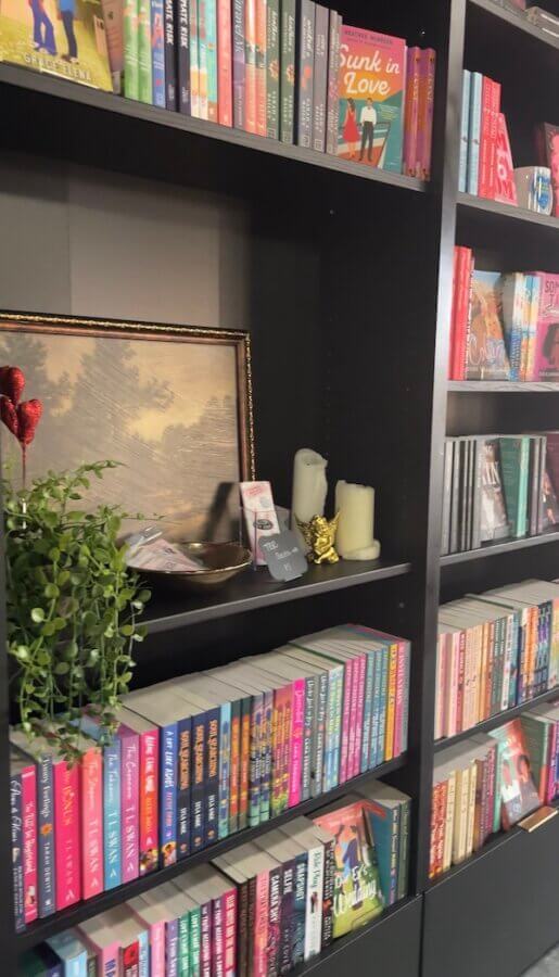 9 New Nashville Retail Spots to Explore - 9 Bookshelves filled with colorful books, decorative candles from Nashville stores, a small plant, a framed painting, and a gold figurine create the perfect space for lovers of reading and Nashville shopping.