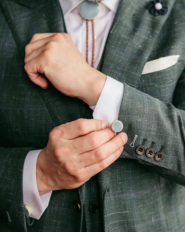 9 New Nashville Retail Spots to Explore - 5 A person in a green plaid suit adjusts a cufflink on their white shirt sleeve, showcasing refined style.