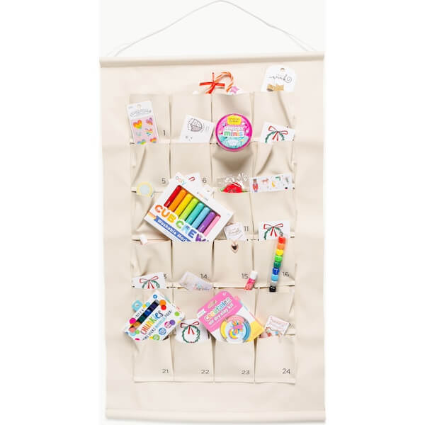The BEST Advent Calendars for 2025 - 16 A cream-colored hanging organizer with 24 numbered pockets, perfect for advent calendars, each holding various small art and craft supplies like markers, crayons, and stickers.