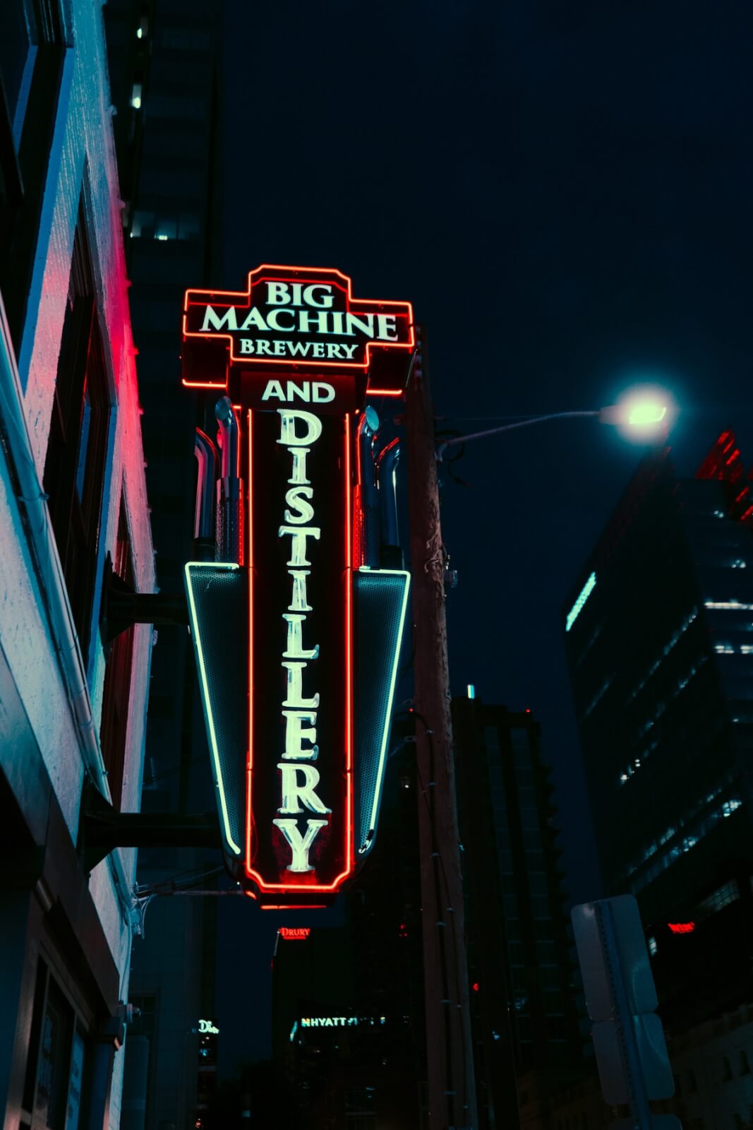 Neon sign reading "Big Machine Brewery and Distillery" glows at night on the side of a building, highlighting one of Nashville's local favorites in an urban area.