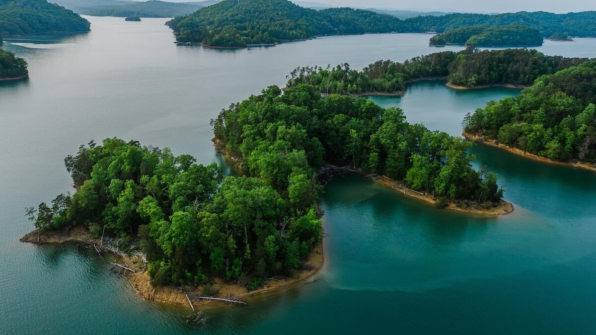 5 Beloved Tennessee Destinations for Adventure Lovers - 5 Aerial view of several small, forested islands surrounded by calm blue-green water in a lake, offering a glimpse of Tennessee outdoor escapes with distant hilly shoreline in the background.