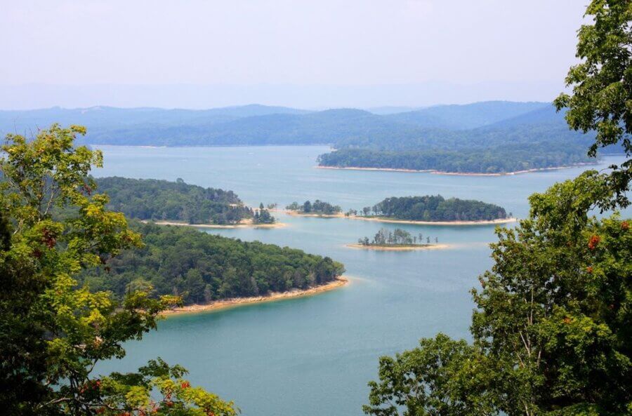 5 Beloved Tennessee Destinations for Adventure Lovers - 12 A scenic view of a lake with several tree-covered islands, surrounded by forested hills under a hazy sky—perfect for those seeking Tennessee outdoor adventures.