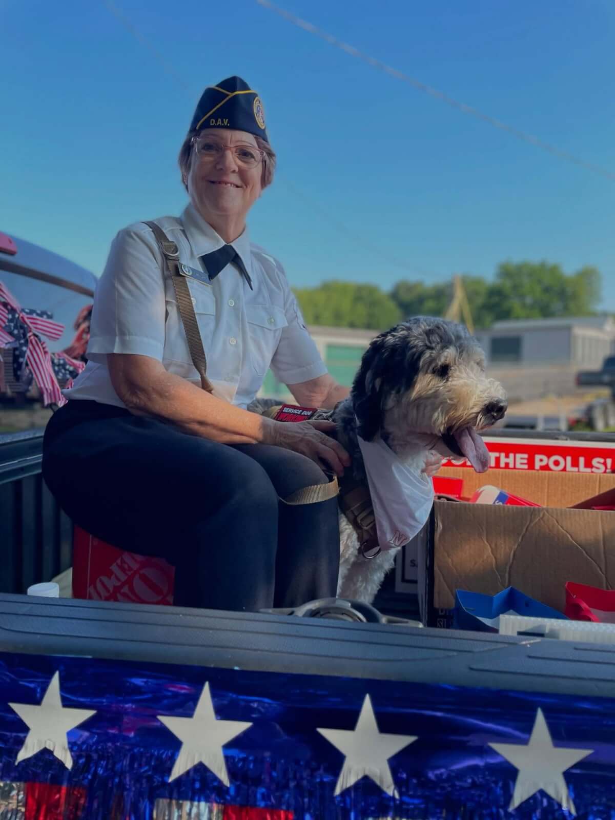 6 Organizations Pairing Canines and Veterans Across the South - 7 A woman in a military uniform sits beside her canine companion on a decorated parade float featuring patriotic stars and red, white, and blue decorations with Warrior Freedom Service Dogs.