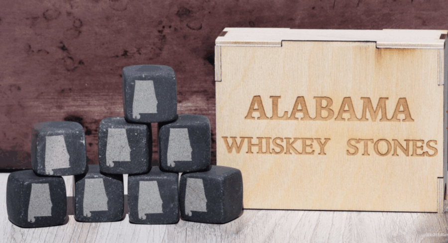 50 Under $50: Your BHAM Holiday Gift Guide - 43 A set of black whiskey stones with the outline of Alabama, stacked beside a wooden "Alabama Whiskey Stones" box—an ideal pick for holiday gifts under $50 and featured in the Birmingham holiday gift guide.