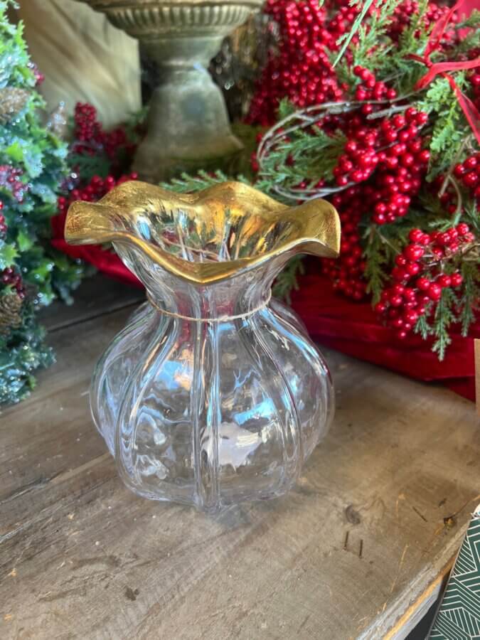 50 Under $50: Your BHAM Holiday Gift Guide - 25 A clear glass vase with a wavy gold rim sits on a wooden surface, surrounded by festive red berries and greenery—an elegant addition to any Birmingham holiday gifts or gifts under $50.