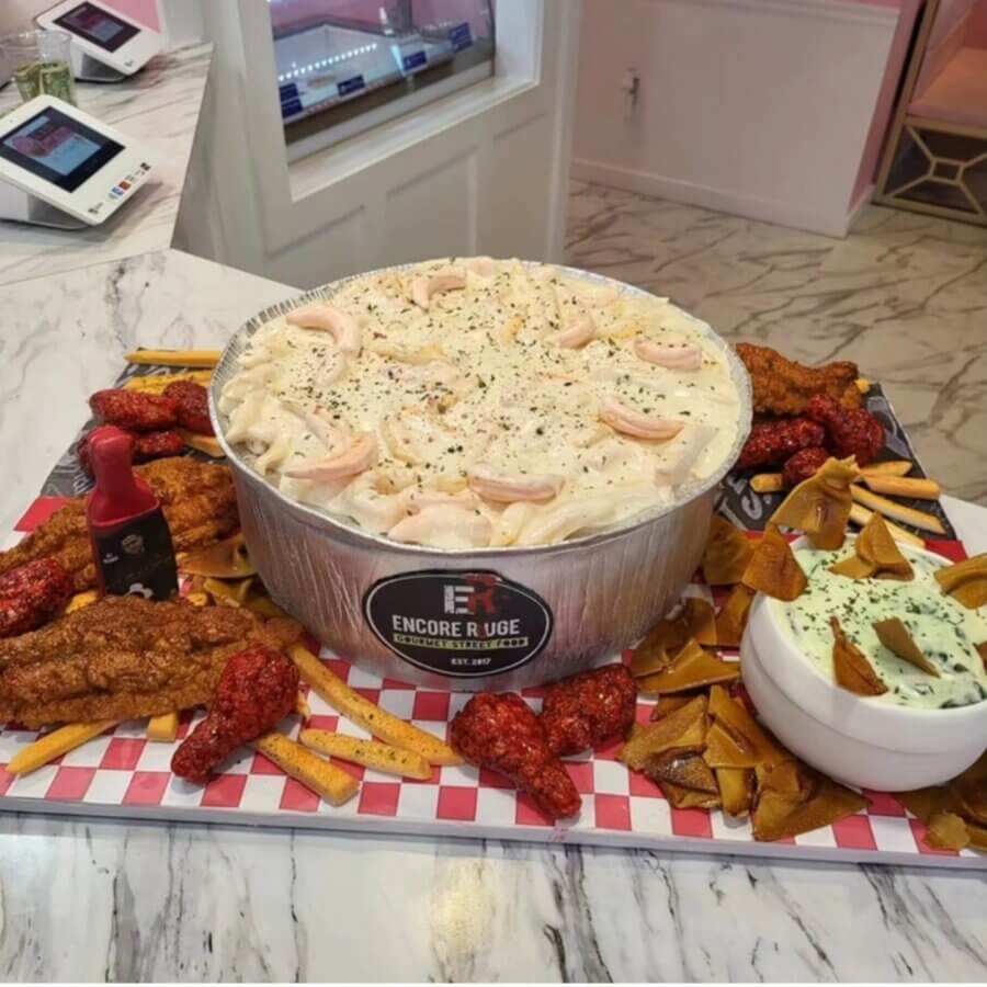 Meet Kristal Bryant of K&J’s Elegant Pastries & Creamery - 8 Large tray with a tub of creamy pasta, fried chicken strips, sauced wings, fries, tortilla chips, a dip bowl, and mini hot sauce—beautifully arranged on checkered paper by our designer chef in an inviting restaurant setting.