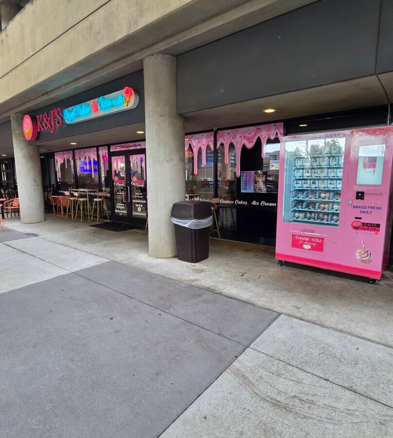 Meet Kristal Bryant of K&J’s Elegant Pastries & Creamery - 7 Exterior of K&J's Elegant Pastries & Cream shop with pink signage, tables and chairs outside, and a pink vending machine to the right of the entrance.