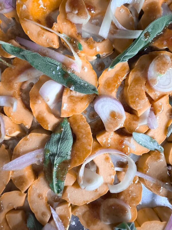Cooking Unscripted: Roasted Delicata Squash with Apples & Sage - 3 Sliced shallots and fresh sage leaves mingle with roasted delicata squash, all coated in oil and ready for the oven.