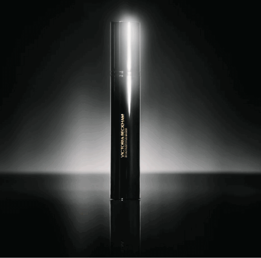 23 Luxurious Nashville FINDS for Holiday 2025 - 18 A sleek, black cylindrical bottle with a glowing light behind it, labeled “Victoria Beckham” in gold text, stands on a reflective surface against a dark background—perfect for adding a touch of luxe to your holiday celebrations.