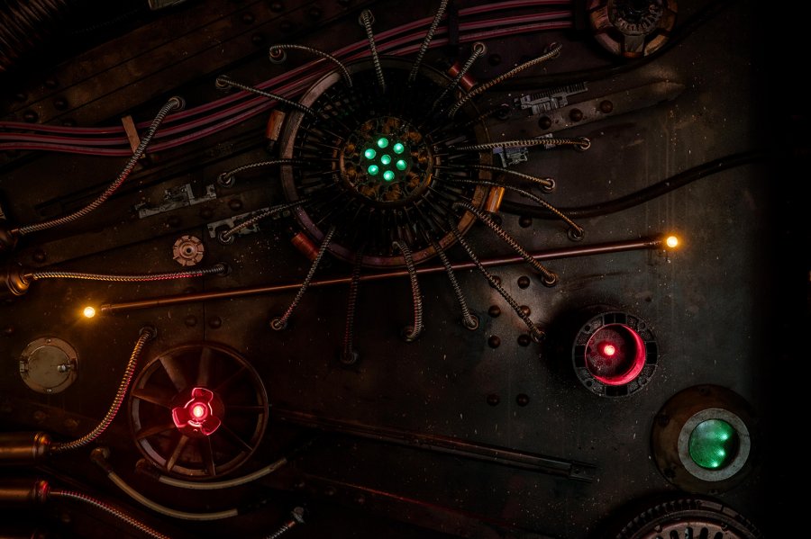 A Sneak Peek at Memphis's Most Buzzed-About New Experience - 5 A metallic control panel with glowing green, red, and yellow lights, various wires, pipes, and mechanical components arranged in a radial and linear pattern—perfect for a Baron Von Opperbean adventure for all ages.