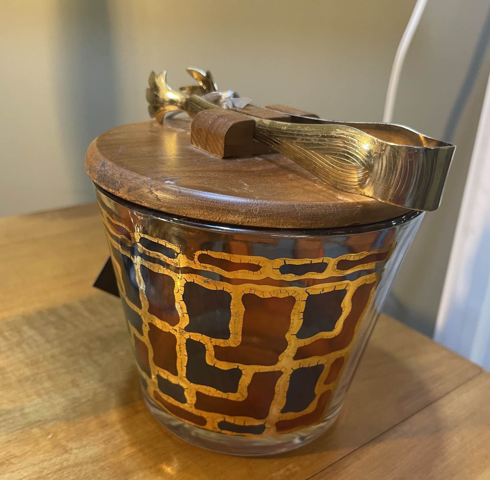 50 Under $50: Your Nashville Holiday Gift Guide - 8 A glass jar with a gold geometric pattern, topped with a wooden lid and a gold decorative spoon, sits on a wooden surfaceβa charming Nashville find perfect for Gifts Under $50 or your Holiday Gift Guide.