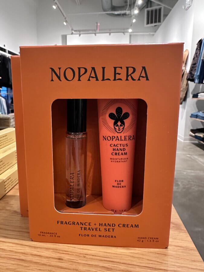 50 Under $50: Your Nashville Holiday Gift Guide - 35 Nopalera Fragrance + Hand Cream Travel Set in Flor de Madera scent displayed on a Nashville store tableβan ideal pick for any Holiday Gift Guide, featuring a 10ml fragrance and 45ml cactus hand cream in orange packaging.