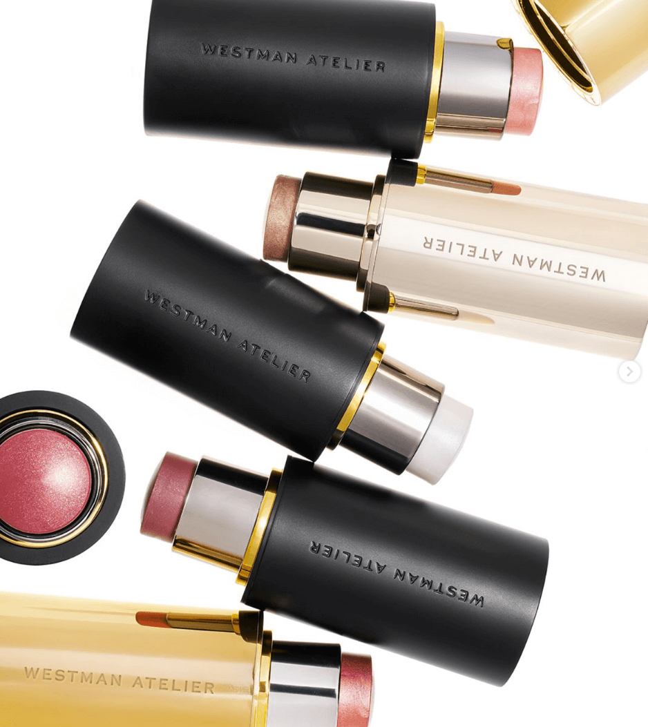 50 Under $50: Your Nashville Holiday Gift Guide - 36 Four Westman Atelier makeup sticks in black and gold tubes, along with a round blush compact, are arranged on a white backgroundβperfect for any Nashville-inspired holiday gift guide.