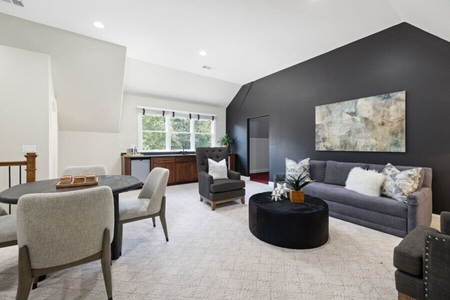 Just Listed! A Franklin Home Where Style & Serenity Coexist - 14 Just Listed: Experience luxury living in this modern Franklin home featuring a gray sofa, round black ottoman, abstract wall art, and a dining area with upholstered chairs by the window. Neutral tones and natural light fill the space.