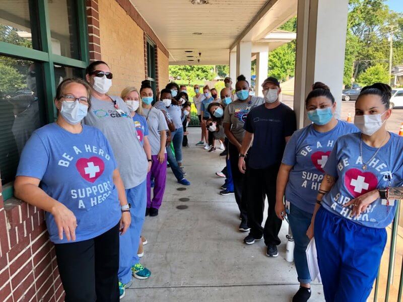 Nashville Toy and Food Drives to Support This Holiday Season - 2 A group of people wearing face masks stand in a line outside a Nashville building; several wear shirts reading "Be a Hero Support a Hero," supporting Holiday Drives for 2025.