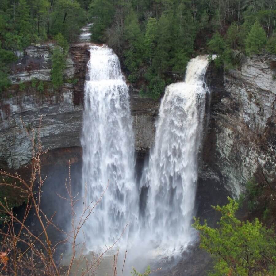 5 Beloved Tennessee Destinations for Adventure Lovers - 14 A large waterfall splits into two streams as it cascades over a rocky cliff surrounded by dense green trees, offering a stunning backdrop for unforgettable Tennessee outdoor adventures.