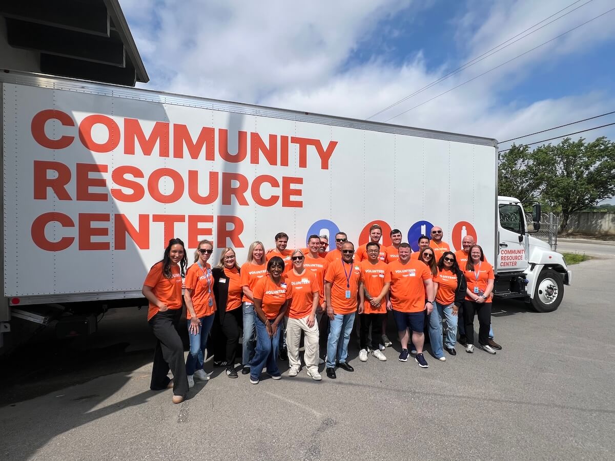 Dignity Starts With a Toothbrush: How The Community Resource Center Quietly Changes Lives in Middle TN - 4 A group of people wearing orange shirts stands smiling in front of a Community Resource Center truck on a sunny day.
