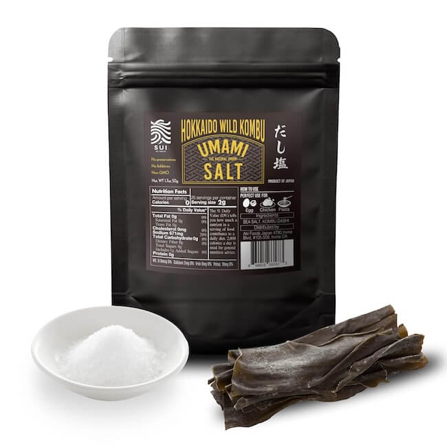 12 Nashville Chefs Share Their Go-To Culinary Gifts to Give - 10 A chef-approved black package labeled "Hokkaido Wild Kombu Umami Salt" stands behind a white bowl of salt and a bundle of dried kombu seaweed—perfect for unique Holiday gifts in Nashville.