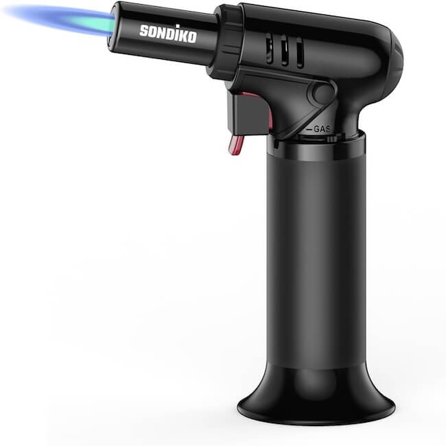 12 Nashville Chefs Share Their Go-To Culinary Gifts to Give - 13 A black Sondiko butane torch emits a blue flame from its nozzle, featuring a visible trigger and gas adjustment control—perfect for culinary insiders in Nashville or as standout holiday gifts.
