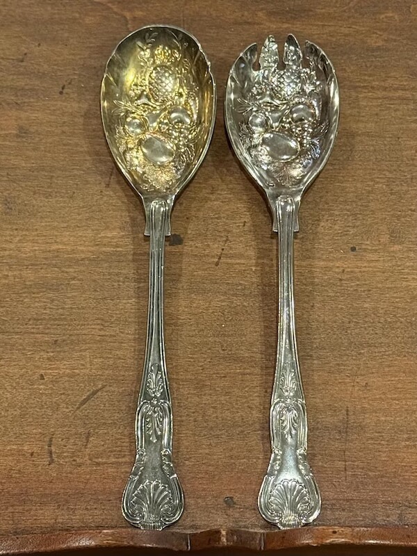 12 Nashville Chefs Share Their Go-To Culinary Gifts to Give - 5 Two ornate silver serving utensils featuring embossed fruit designs and matching decorative handles rest on a wooden surface—an elegant find for culinary insiders seeking unique Nashville holiday gifts.
