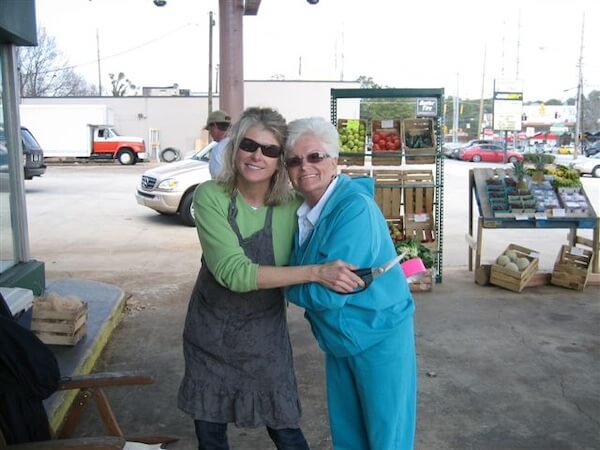 Meet Kim Wilson of Atlanta's Beloved Lucy's Market - 3 Two women stand and smile at Lucy's Market, with fruit and produce crates visible in the background.