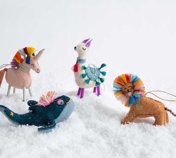 14 Southern Ornament & Stocking Shops We Love - 11 Four colorful felt animal ornamentsβa unicorn, llama, whale, and lionβstand on a layer of artificial snow, making charming Christmas decorations from Southern ornament purveyors.