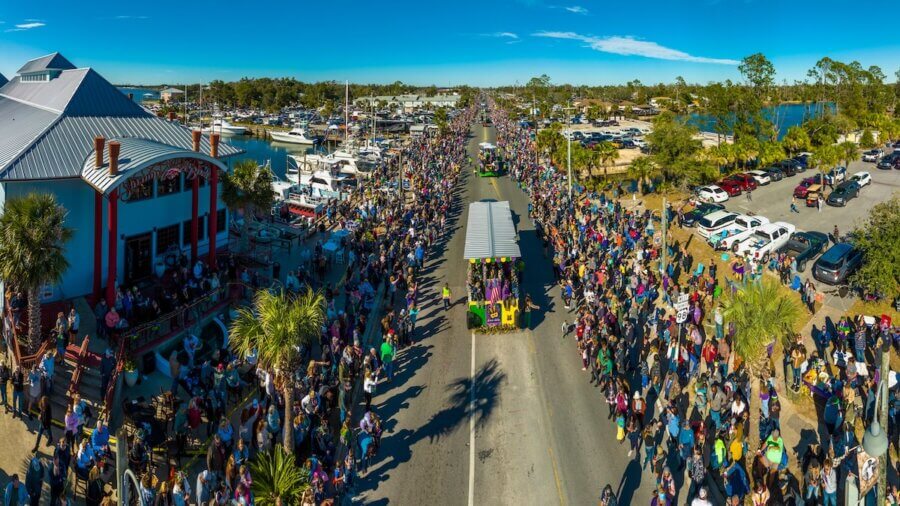 Panama City’s Multi-Coastal Story: History, Culture & Life on the Bay - 7 Aerial view of a parade with a decorated float moving down a street in Panama City FL, lined with large crowds on both sides under a clear blue sky, just minutes from the beach—a perfect scene for travel lovers.