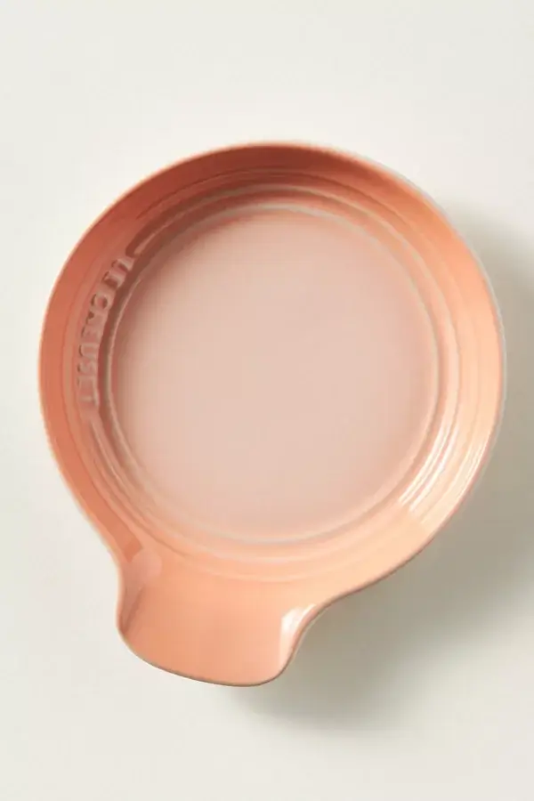 10 Gifts For Bakers Under $100 - 6 A round, peach-colored ceramic dish with a handle and βLe Creusetβ embossed on the rim, set against a plain light backgroundβan ideal baking gift and perfect for gifts under $100.