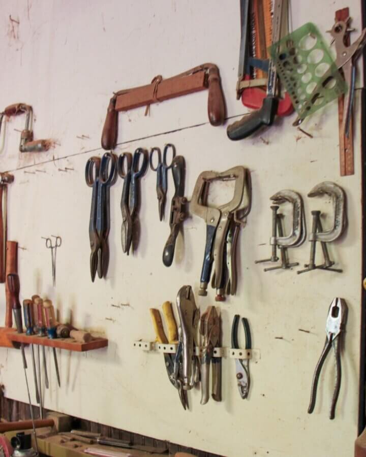 Stop Donating These 5 Items — They May Be Worth Serious Cash - 5 Various hand tools, including pliers, clamps, scissors, and screwdrivers worth money, are neatly organized and hanging on a wall in a workshop—these valuable items add function and order to the workspace.