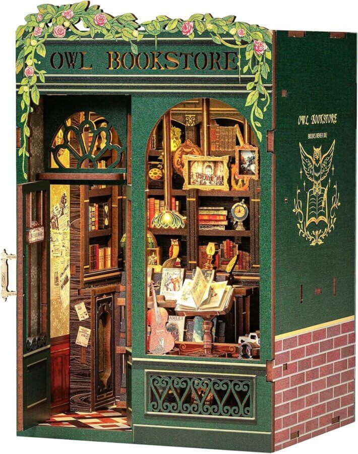 10 Unique Gift Ideas for Book Lovers - 10 A miniature model of a green bookstore called "Owl Bookstore," featuring detailed bookshelves, framed art, and various objects visible through the front windows and open door—a charming gift idea for book lovers and readers alike.