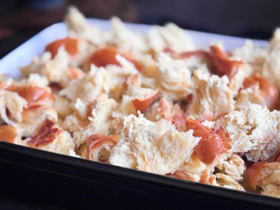 Eggnog French Toast Bake โ Perfect for the Holidays! - 4 A close-up of torn bread pieces spread out in a rectangular baking tray, ready to become a delicious Cooking Unscripted Overnight French Toast Bake.