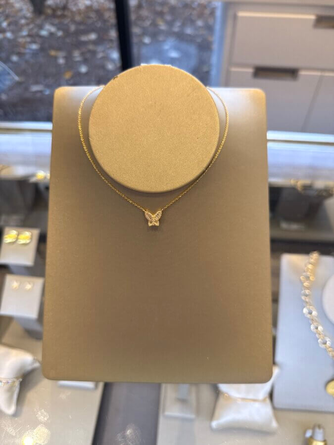 23 Luxurious Nashville FINDS for Holiday 2025 - 9 A gold necklace with a small butterfly-shaped pendant displayed on a stand in a jewelry store, perfect for those seeking expensive gift ideas.