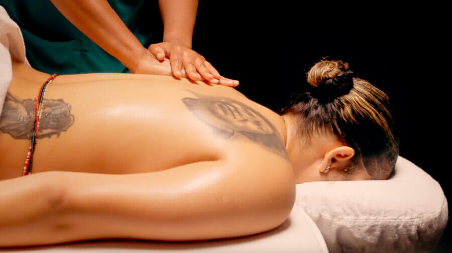 The Best Day Spas in Memphis for a Blissful Escape - 5 A person with tattoos enjoys pampering at one of Memphis' relaxing day spas, receiving a back massage while lying face down on a massage table with a white towel under their head.