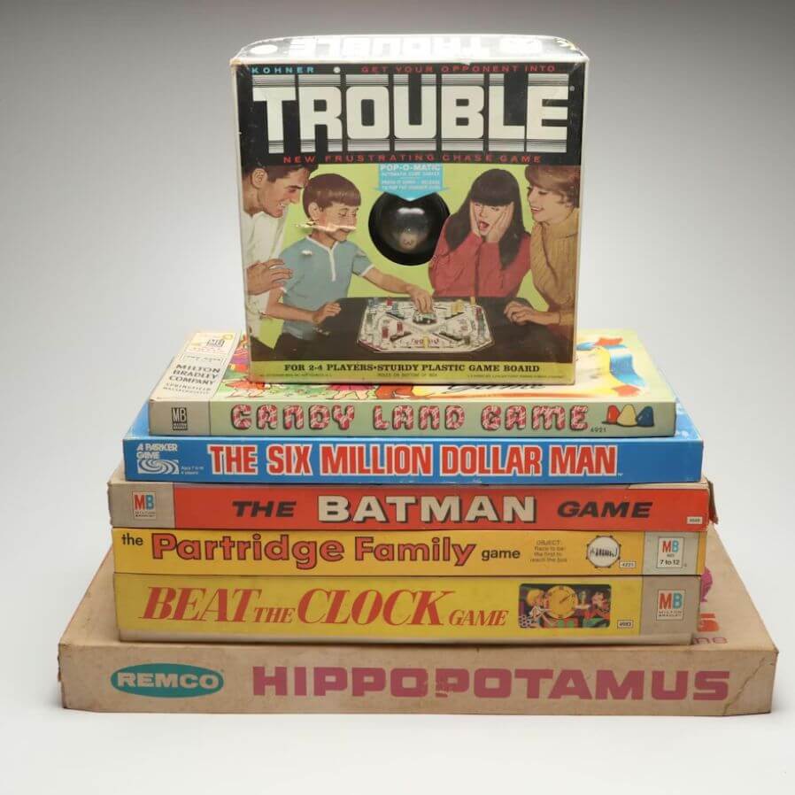Stop Donating These 5 Items — They May Be Worth Serious Cash - 6 A stack of vintage board games, including Trouble, Candy Land, and Batman—these could be valuable items. Stop donating treasures like these; they might actually be items worth money.