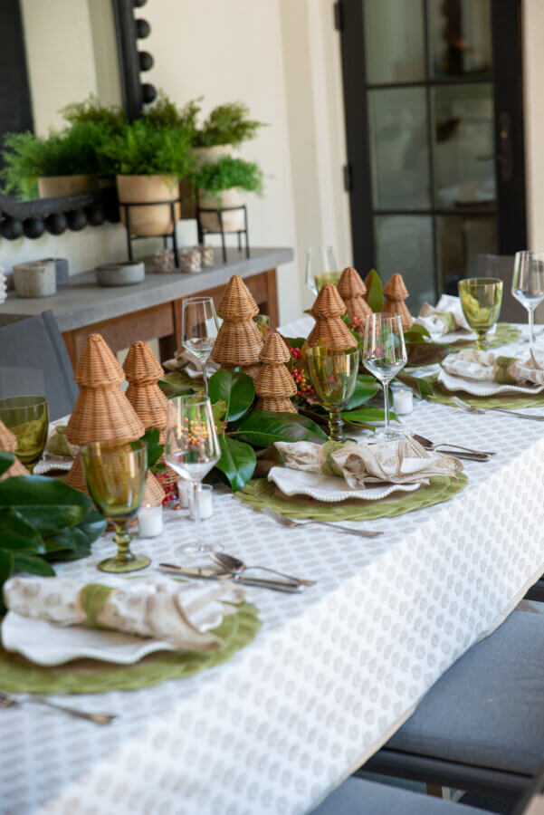 An Event Planner's Guide to Holiday Hosting: Setting the Table, the Mood, and More - 5 Outdoor dining table with neutral-patterned cloth and small woven tree decorations.