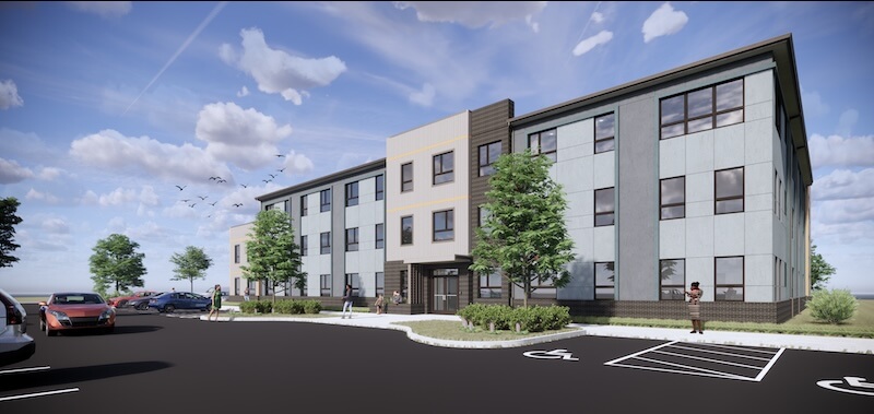 This Nashville Mom Rebuilt Her Life at Renewal House - 3 Renewal House is a three-story modern apartment building with large windows, a parking lot in front, trees, and a few people walking nearby under a partly cloudy sky.