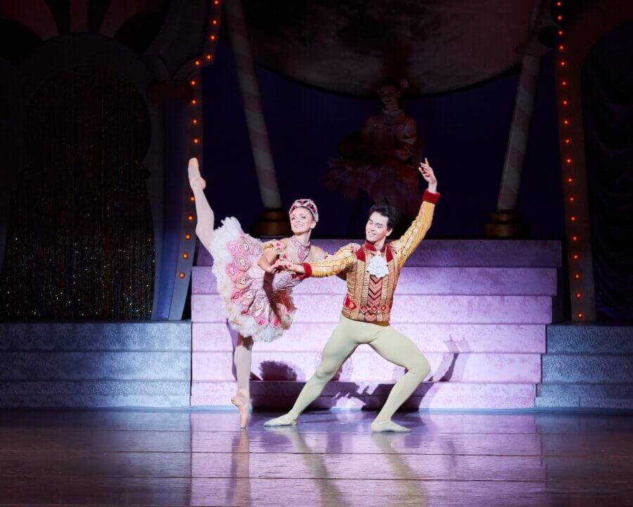 Meet the Star of Nashville Ballet’s Nutcracker - 5 Two ballet dancers, including Colette Tilinski in ornate costumes, perform a pose on stage with a decorative set and soft lighting in the background.