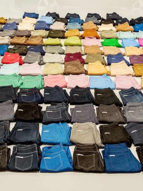 Blue Delta Jeans: Made in MS, One Pair at a Time - 5 Rows of neatly folded pants in various colors, arranged on a white surface for an organized and colorful display—crafted with care by Blue Delta Jeans.