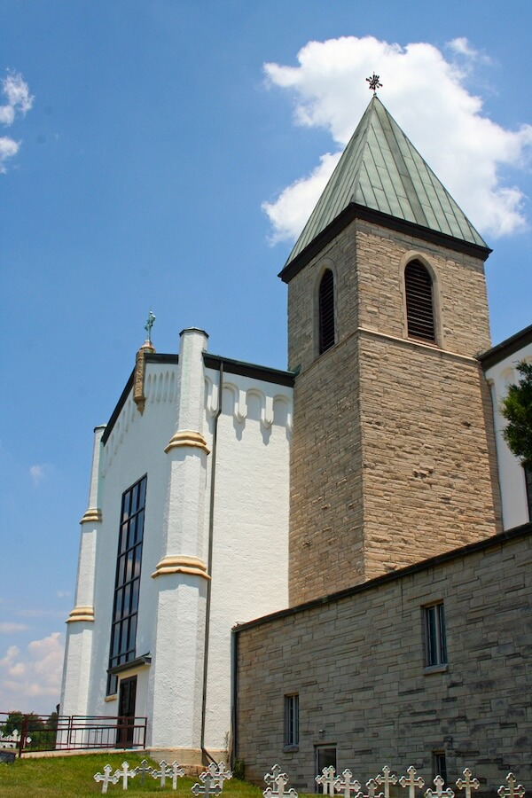 10 Digital Detox Destinations Around the South - 3 A church building with a tall stone bell tower, white walls, arched windows, and a cross at the steeple stands under a blue sky—one of the best places for digital detox destinations, inviting peace and quiet away from screens.