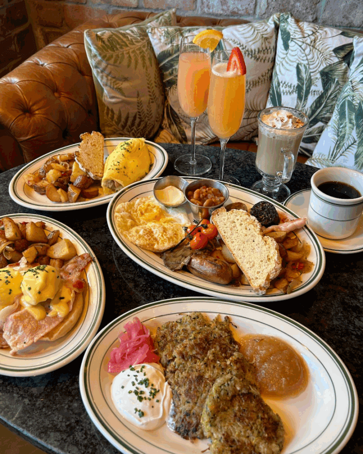 20+ Memphis Restaurants Open on New Year's Day - 4 A table set with plates of brunch food—omelets, eggs benedict, hash browns, breakfast sides—and drinks like coffee, cappuccino, and mimosas.