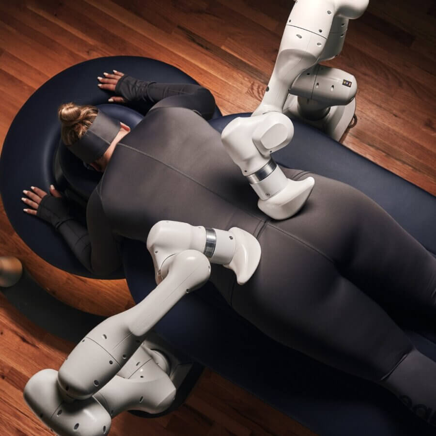 15 Decadent Nashville Spa Treatments to Gift - 5 Person lying face down on a massage table, receiving a massage from robotic arms on their back and legs in a modern setting—an innovative Nashville spa experience perfect as a spa gift or for indulging in the latest Nashville spa treatments.