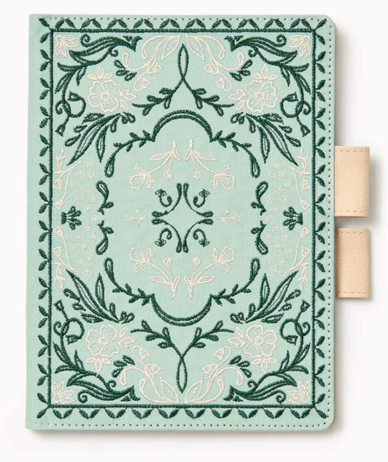 17 Birmingham FINDS for the New Year - 14 A light green fabric notebook cover with an ornate, embroidered floral pattern in green and white—one of our latest FINDS in Birmingham—features two beige pen loops on the right side.
