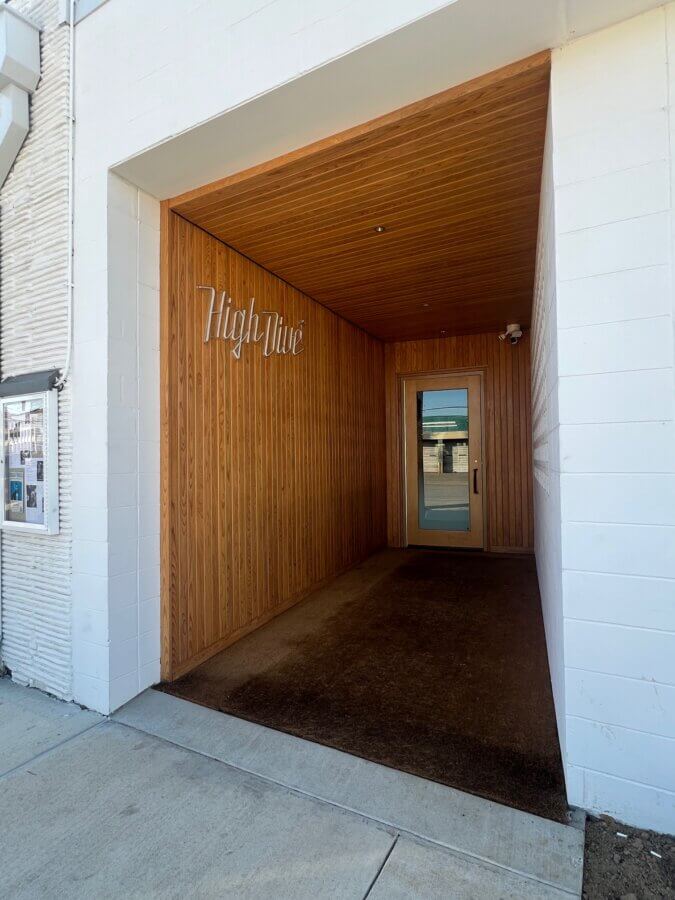 10 New Birmingham Restaurants to Try This Month - 21 A recessed wooden entrance with a glass door, white exterior walls, and "Highline" in metallic letters on the left interior wall makes this one of the Birmingham restaurants to try this month.