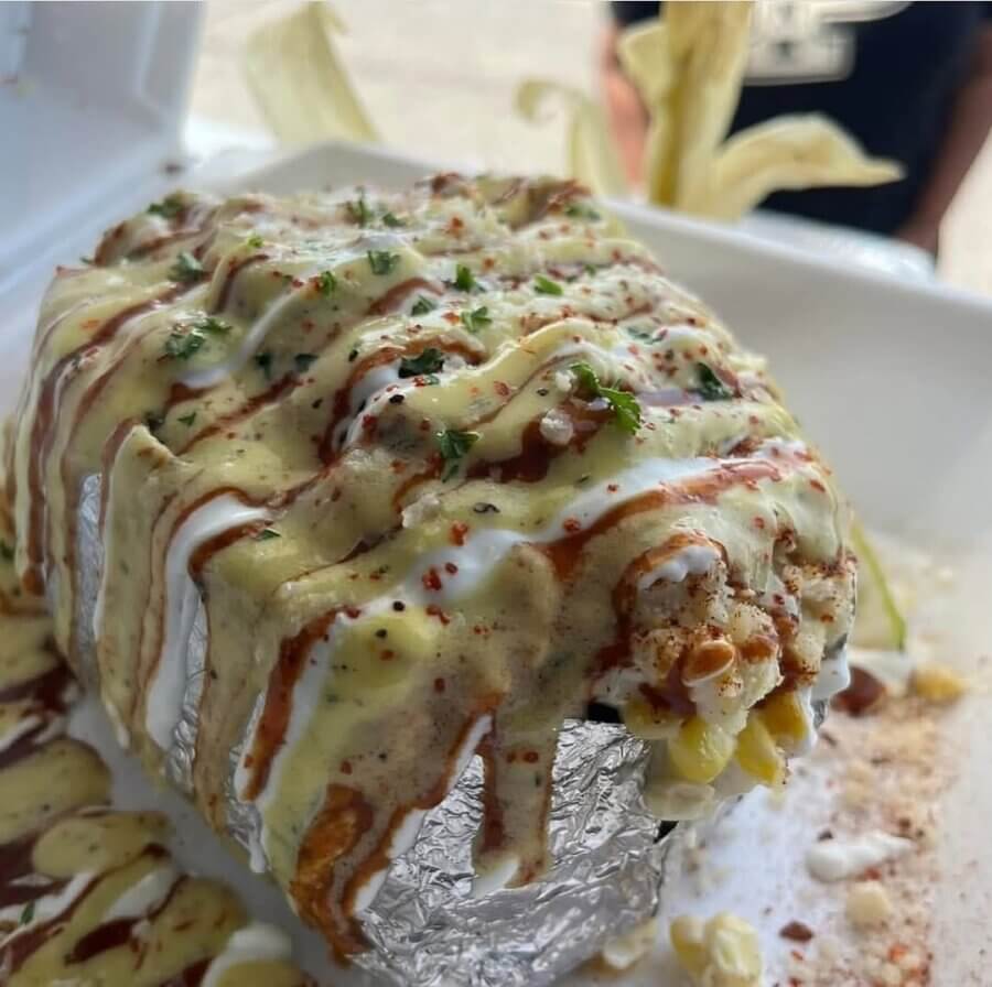 Aww Shucks! Meet the Woman Behind This Plant-Based BHAM Favorite - 6 A foil-wrapped baked potato is topped with corn, creamy sauces, seasonings, and herbs, served in a white foam container—perfect for enjoying at your favorite plant-based food truck when you eat out.