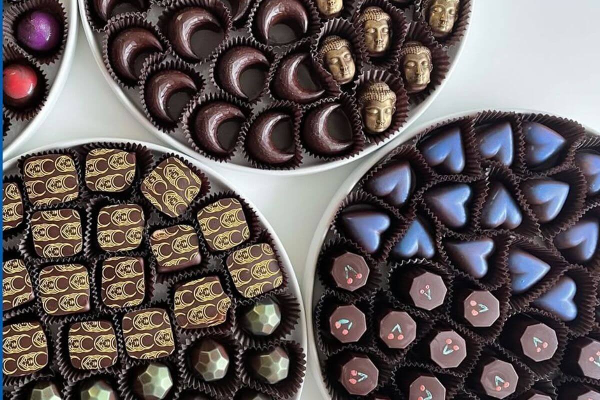 Four round trays filled with decadent chocolate in various shapes—moons, hearts, geometric patterns, and faces—make a delightful treat perfect for Valentine’s Day from Chocolata.