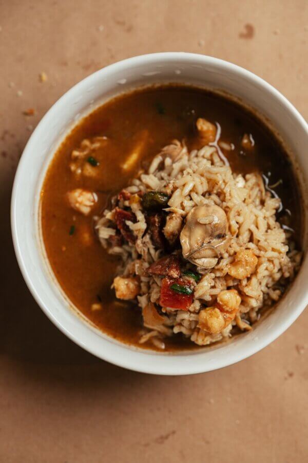 A Southern Chef's Secret to a Cleaner Kitchen in 2026 (It’s Not What You Think) - 7 A white bowl filled with rice, vegetables, chickpeas, and brown broth sits on a tan surface.