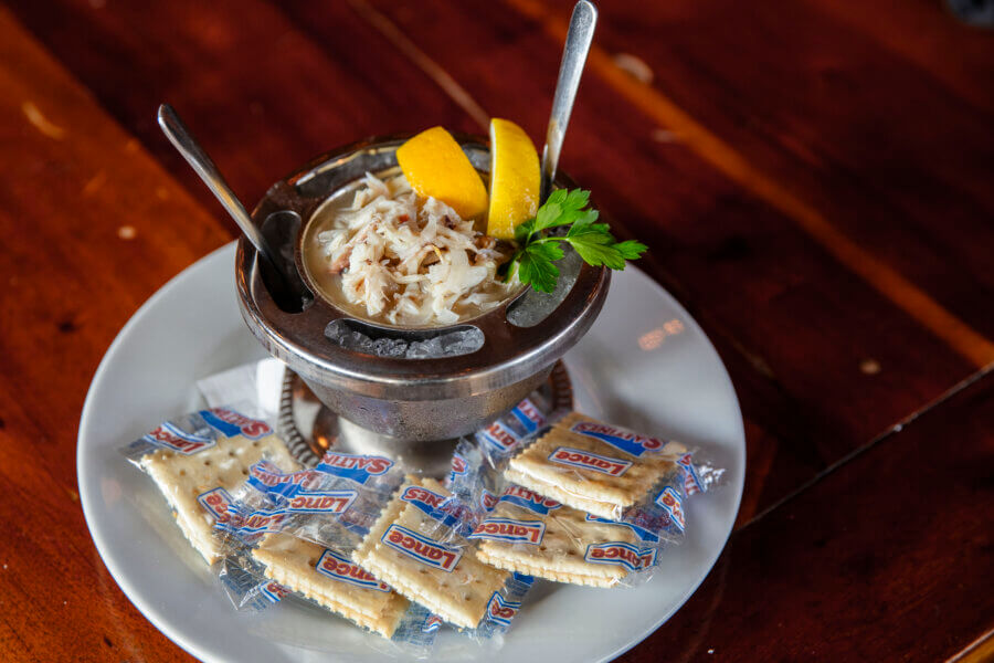 A Southern Chef's Secret to a Cleaner Kitchen in 2026 (It’s Not What You Think) - 5 A bowl of Dyon's popular West Indies Salad with two lemon wedges, parsley, and two spoons, served on ice with saltine crackers.