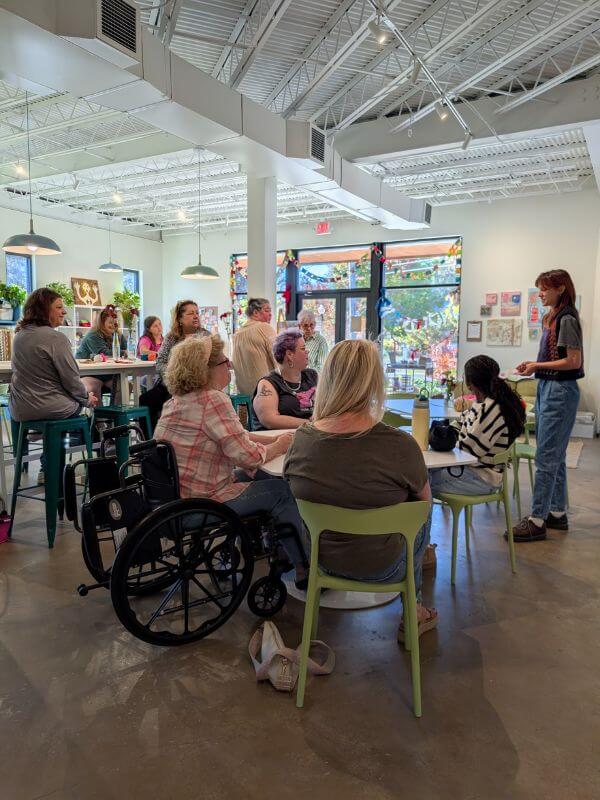 This BHAM Engineer Creates Community Through ... Crafting! - 7 A group of women sit at The Craft Room's craft tables listen to Rachel Brockwell introduce her crochet workshop.