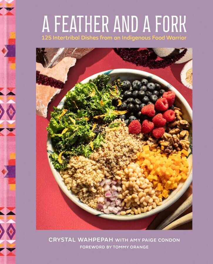 2026 Cookbook Releases We Can't Wait to Snag - 8 A bowl with quinoa, kale, raspberries, blueberries, orange slices, and white beans sits on a red surface on the cover of "A Feather and a Fork" by Crystal Wahpepah—one of the most anticipated upcoming cookbooks.