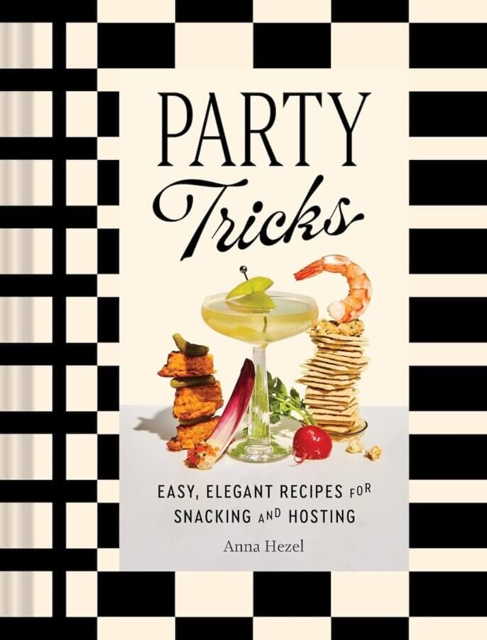 2026 Cookbook Releases We Can't Wait to Snag - 6 Book cover for "Party Tricks" by Anna Hezel, an upcoming cookbook featuring a cocktail, shrimp, stacked snacks, and vegetables against a black-and-white checkered border—one to watch among 2026 cookbook releases.